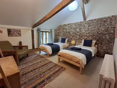 two beds in a room with a stone wall at Colemans Farm Barn- Unique, Rustic & Peaceful Barn - Essex countryside in Finchingfield