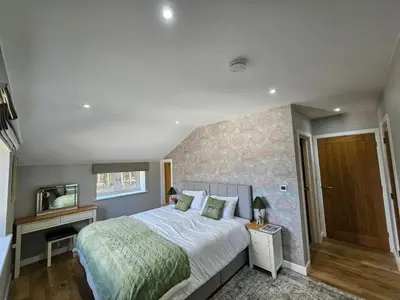 a bedroom with a large bed and a mirror at Bramley Suite - The Apple Barn in Pettistree