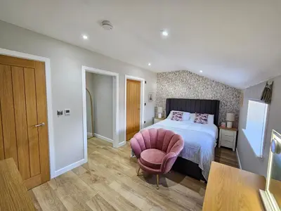 a bedroom with a bed and a pink chair at Bramley Suite - The Apple Barn in Pettistree