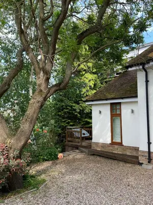 a small white building with a bench next to a tree at Primrose Lodge in Maldon in Maldon