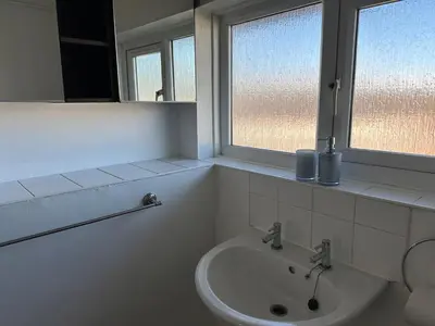 a white bathroom with a sink and two windows at Place to stay up Ipswich near the train station, football stadium, waterfront in Ipswich