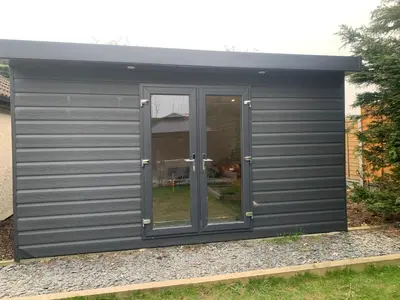 a grey garage with a door and a window at Sunnyside guest house in Latchingdon and Snoreham