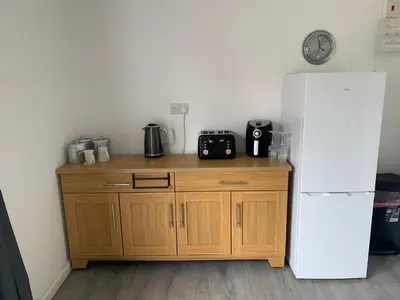 a kitchen with a wooden cabinet next to a refrigerator at Sunnyside guest house in Latchingdon and Snoreham