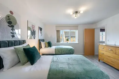 a bedroom with two beds and a dresser at Cambridge 5 Bedrooms Sleeps 10 Free Parking 4 Bathrooms in Long Stanton