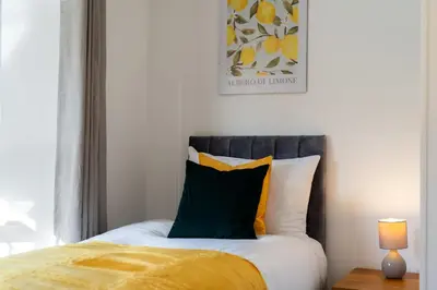 a bedroom with a bed with yellow and white pillows at Cambridge 5 Bedrooms Sleeps 10 Free Parking 4 Bathrooms in Long Stanton