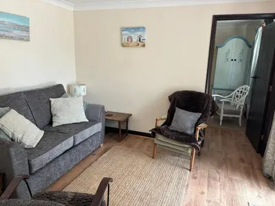 a living room with a couch and a chair at Fushia Chalet a lovely little rural retreat in Saxtead