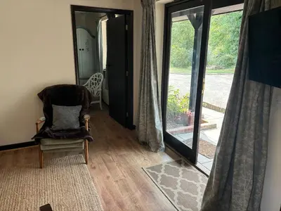 a room with a chair and a sliding glass door at Fushia Chalet a lovely little rural retreat in Saxtead