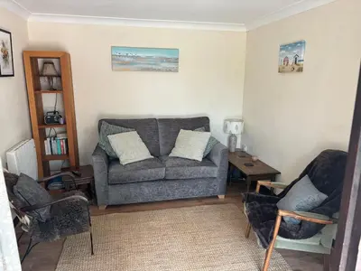a living room with a couch and two chairs at Fushia Chalet a lovely little rural retreat in Saxtead