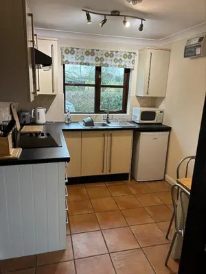 a kitchen with white cabinets and a sink and a window at Fushia Chalet a lovely little rural retreat in Saxtead
