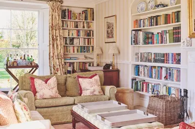 a living room with a couch and shelves of books at Hockham Grange in Hockham