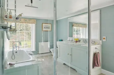a bathroom with a tub and a sink and a mirror at Hockham Grange in Hockham