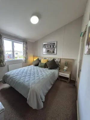 a bedroom with a large bed and a window at The Retreat 2 bedroom lodge with sauna! in Walton-on-the-Naze