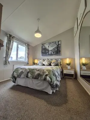 a bedroom with a large bed and a large window at The Retreat 2 bedroom lodge with sauna! in Walton-on-the-Naze
