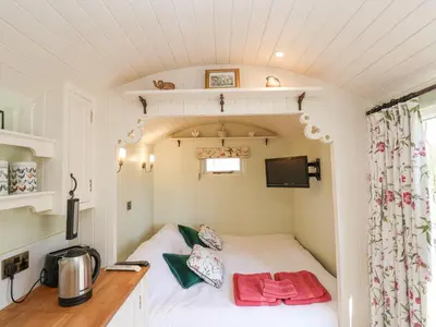 a small bedroom with a bed in a tiny house at Woodlands Retreat Shepherd's Hut in Woodbridge