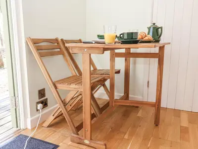 a wooden table with a chair next to a table at Woodlands Retreat Shepherd's Hut in Woodbridge