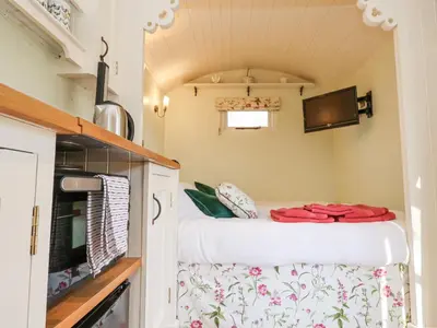 a small kitchen with a bed in a tiny house at Woodlands Retreat Shepherd's Hut in Woodbridge