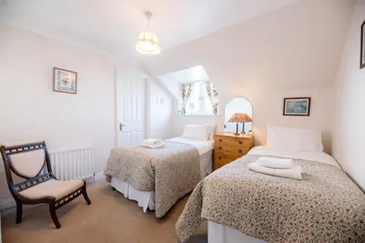 a bedroom with two beds and a chair in it at 3 Barley Lands, Aldeburgh in Aldeburgh
