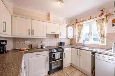 a kitchen with white cabinets and a window at 3 Barley Lands, Aldeburgh in Aldeburgh