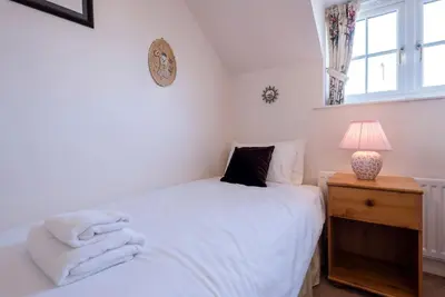 a bedroom with a white bed and a lamp and a window at 3 Barley Lands, Aldeburgh in Aldeburgh