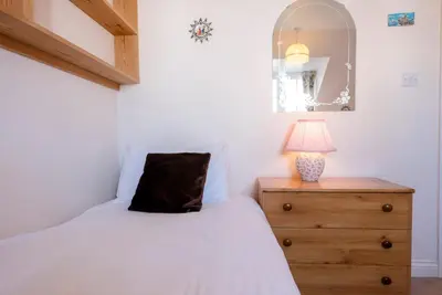 a bedroom with a bed and a lamp on a dresser at 3 Barley Lands, Aldeburgh in Aldeburgh