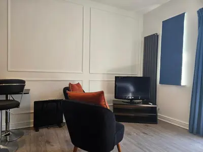 a living room with two chairs and a television at Newly Built Studio Apartment in Stevenage