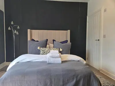 a bedroom with a large bed with black walls at Newly Built Studio Apartment in Stevenage