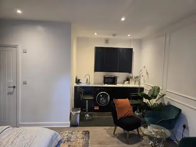 a room with a bed and a kitchen with a desk at Newly Built Studio Apartment in Stevenage