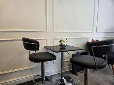 a table with two chairs and a table with flowers on it at Newly Built Studio Apartment in Stevenage