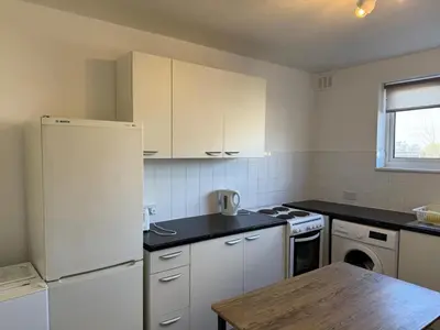 a kitchen with a white refrigerator and a wooden table at 3 Bedroom Apartment in Rayleigh Town Centre with Balcony in Rayleigh