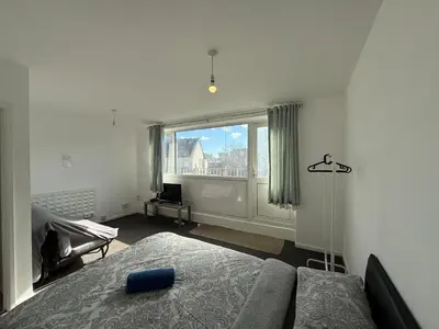 a bedroom with a bed and a large window at 3 Bedroom Apartment in Rayleigh Town Centre with Balcony in Rayleigh