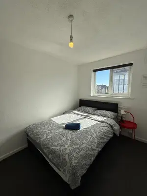 a bedroom with a bed with a blue pillow on it at 3 Bedroom Apartment in Rayleigh Town Centre with Balcony in Rayleigh