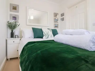 a bedroom with a bed with a green blanket at Bay Tree Cottage in Saxmundham