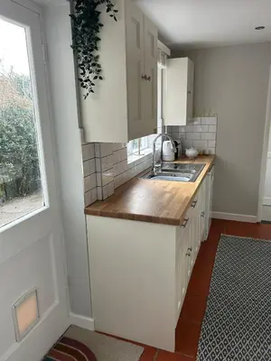 a kitchen with white cabinets and a sink and a window at Victorian Woodbridge cottage in Melton