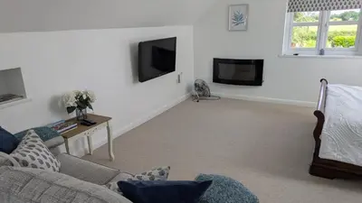 a living room with a couch and a tv at The Lodge in Felsted