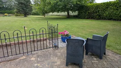 a fence with two chairs and a table with flowers at The Lodge in Felsted