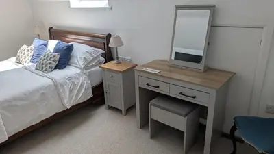 a bedroom with a bed and a dresser with a mirror at The Lodge in Felsted