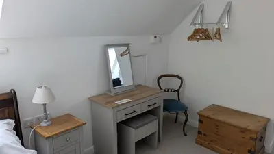 a bedroom with a desk with a mirror and a chair at The Lodge in Felsted