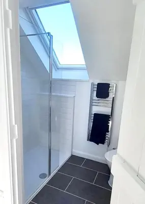 a bathroom with a shower and a toilet with a skylight at The Lodge in Felsted