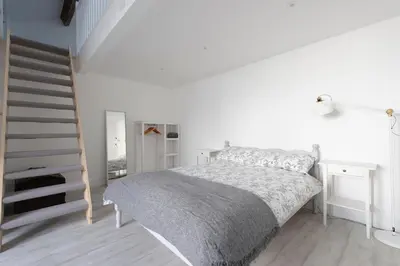 a white bedroom with a bed and a staircase at Historic Old Stables in Bishops Stortford