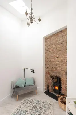 a living room with a couch and a brick fireplace at Historic Old Stables in Bishops Stortford