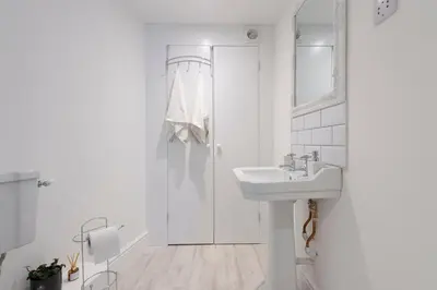 a white bathroom with a sink and a shower at Historic Old Stables in Bishops Stortford