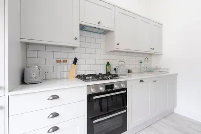 a white kitchen with white cabinets and a stove at Historic Old Stables in Bishops Stortford