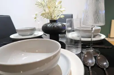 a table with plates and spoons and a bowl on it at Stylish City-Centre Stay in Chelmsford