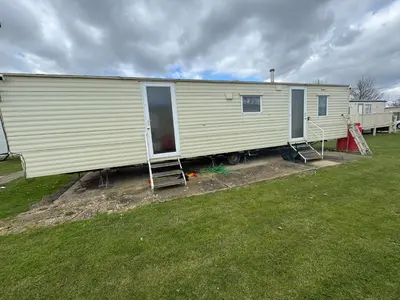a large white mobile home sitting on top of a field at Seawick Holiday Park Caravan Hire in Saint Osyth