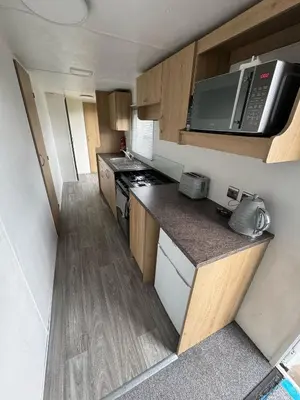 a small kitchen with a stove and a microwave at Seawick Holiday Park Caravan Hire in Saint Osyth