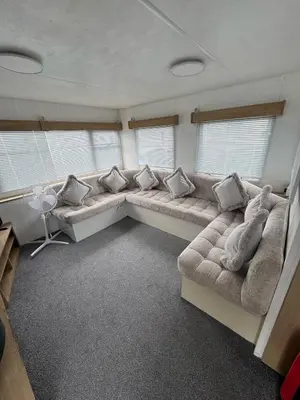 a large living room with a couch and two windows at Seawick Holiday Park Caravan Hire in Saint Osyth