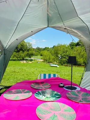 a table in a tent with plates of food on it at Hertford belltent farm stay riverside firepit bbq in Hertford