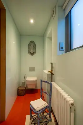 a bathroom with a toilet and a chair in it at Wodehouse, Eco House - Aldeburgh Coastal Cottages in Aldeburgh