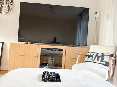 two remote controls sitting on a table in front of a television at Home in Upminster in Upminster