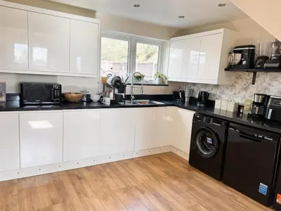 a kitchen with white cabinets and a black dishwasher at Home in Upminster in Upminster